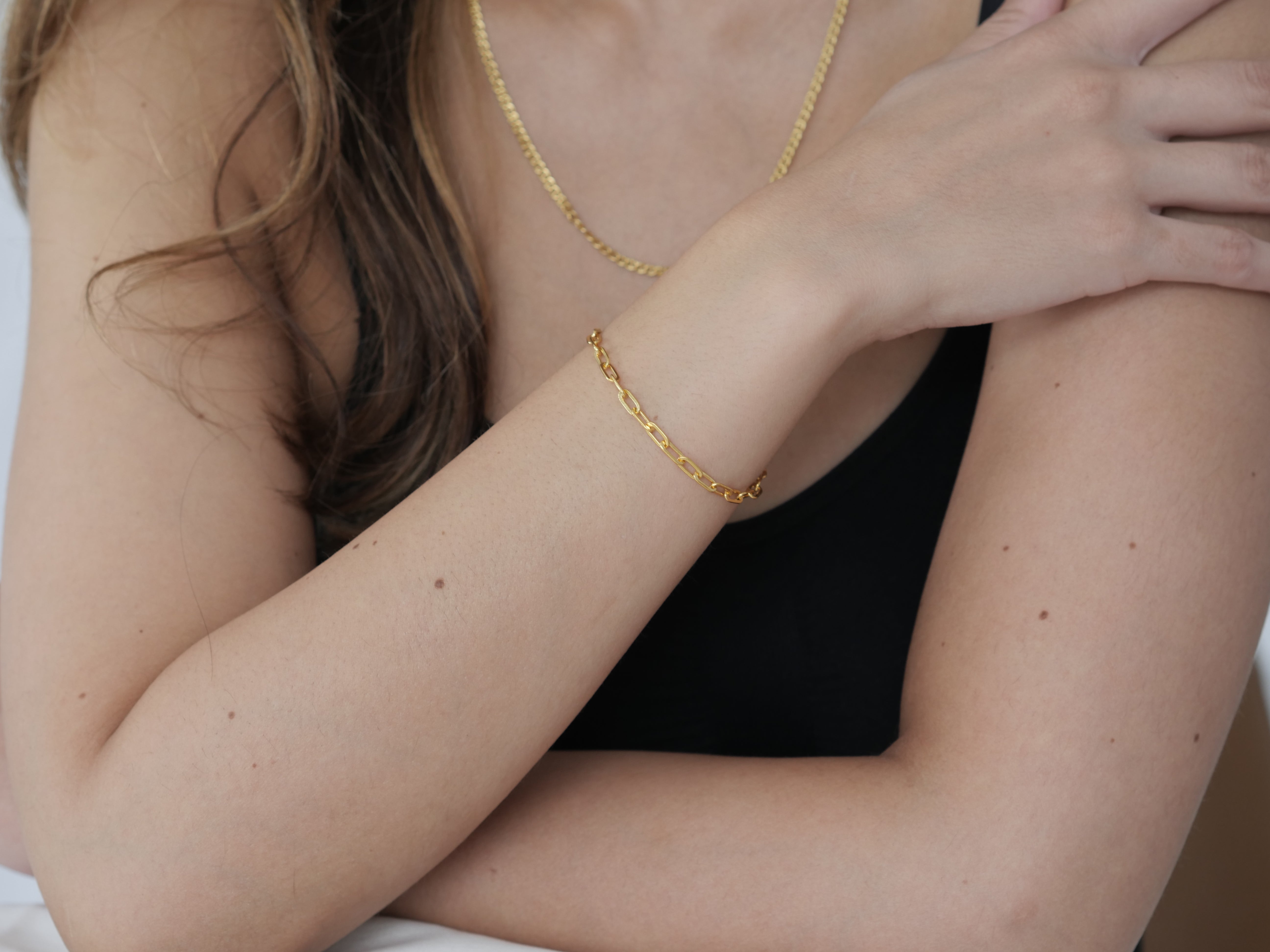 Close-up of a person wearing gold jewelry on a plain background